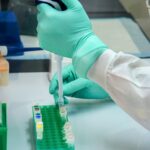 Pesquisador com luvas manipula pipeta e frasco em bancada de laboratório