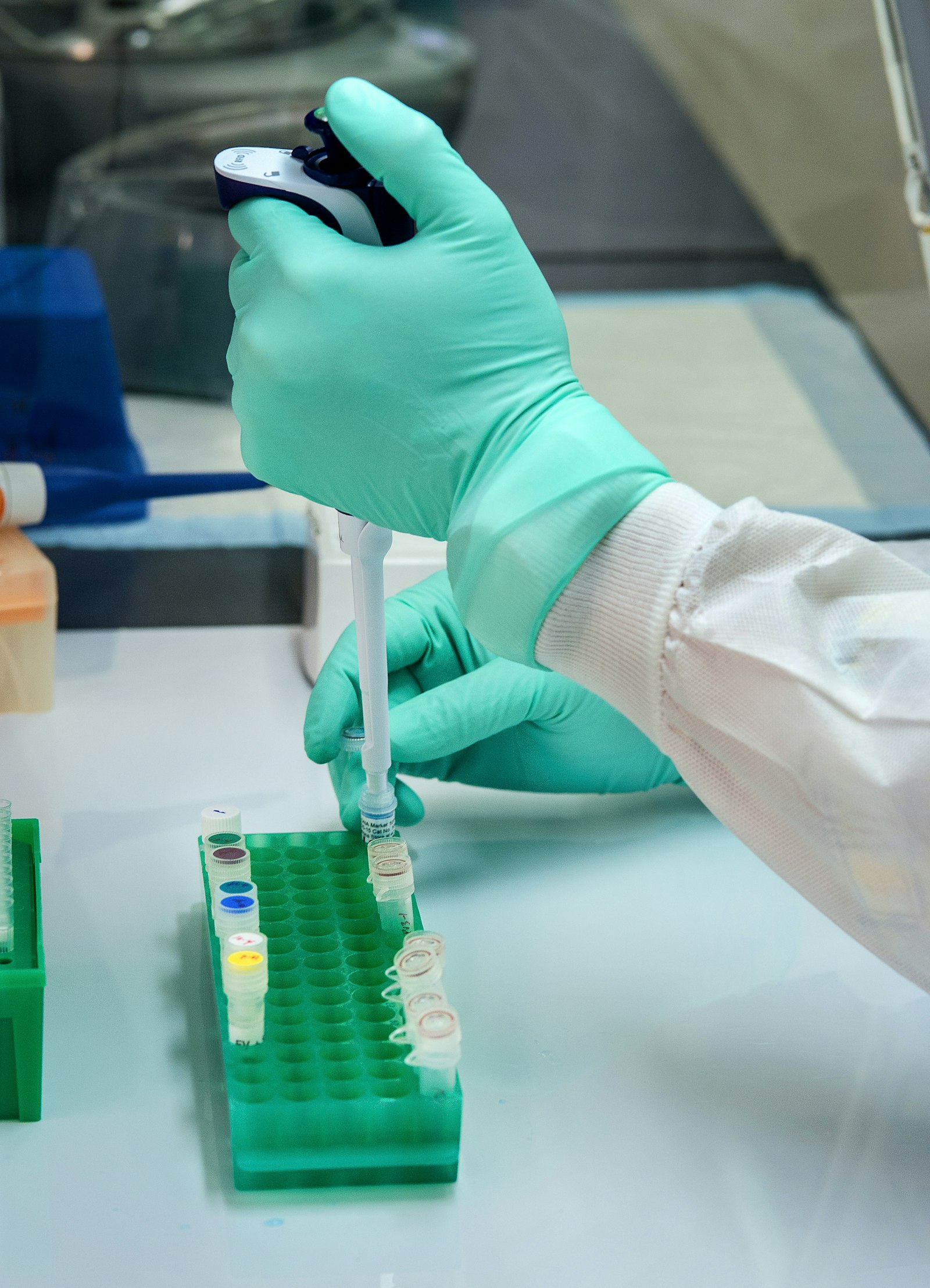 Pesquisador com luvas manipula pipeta e frasco em bancada de laboratório