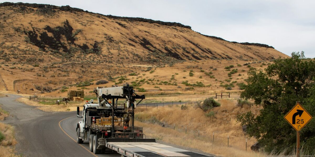 Caminhão de carga trafega por rodovia em região de relevo elevado
