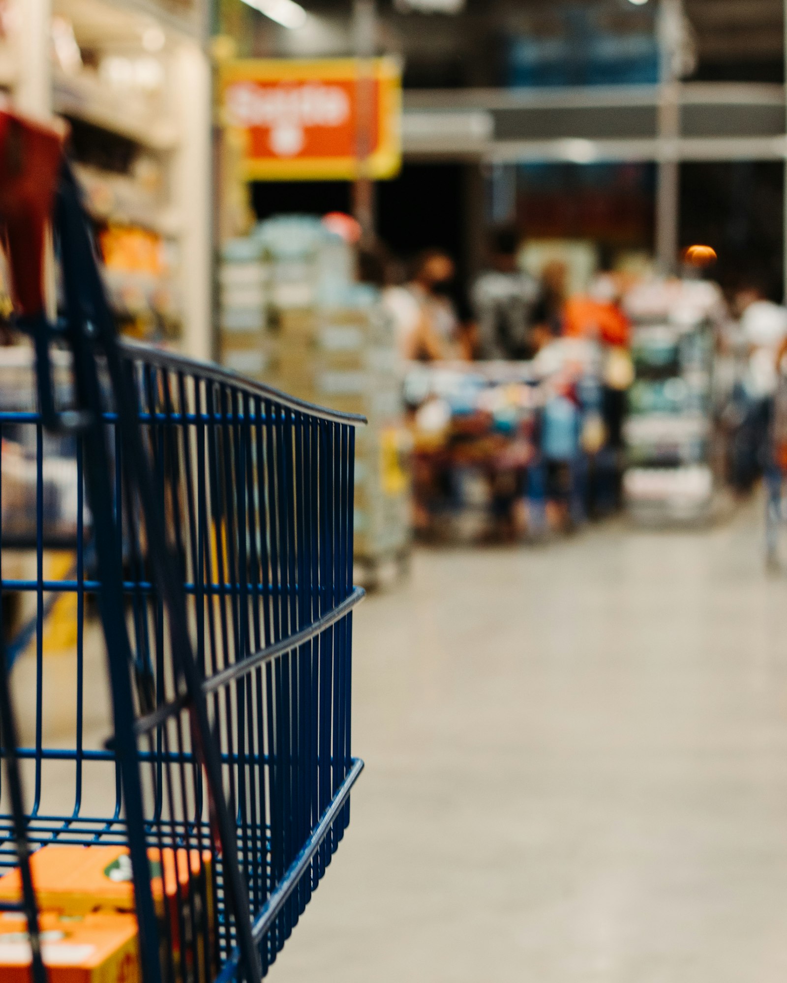 Carrinho de compras azul em corredor de supermercado desfocado