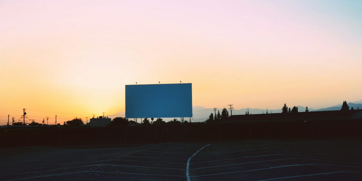 Tela de cinema drive-in e estacionamento vazio ao pôr do sol