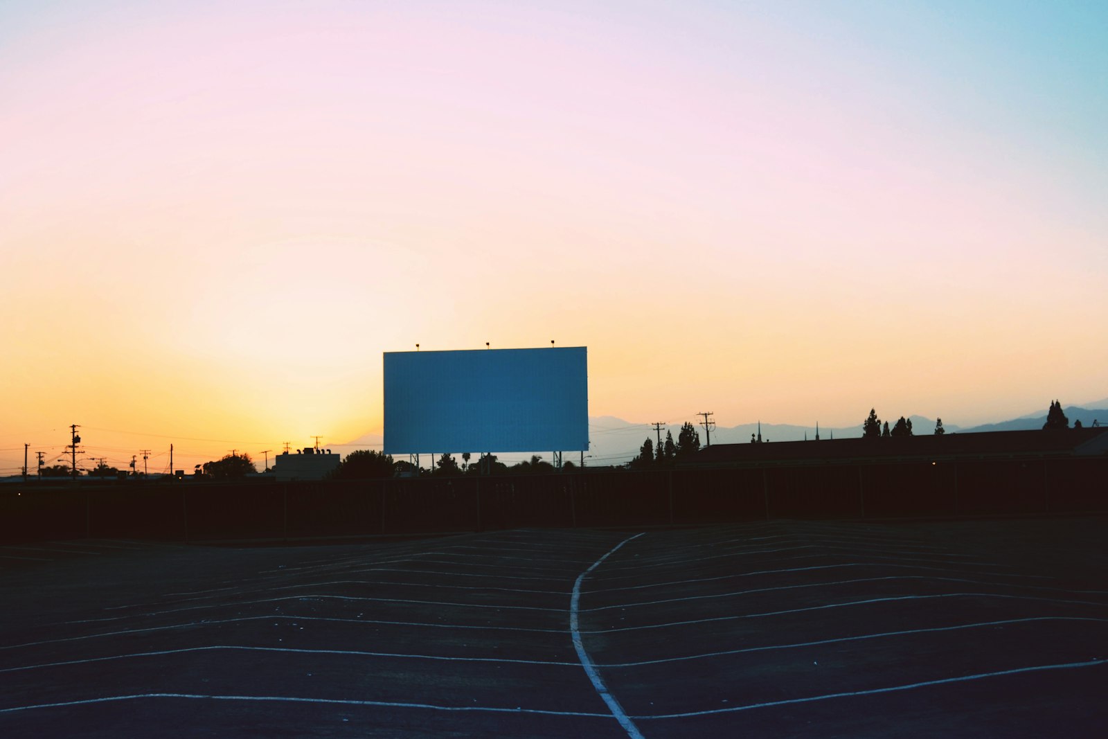 Tela de cinema drive-in e estacionamento vazio ao pôr do sol