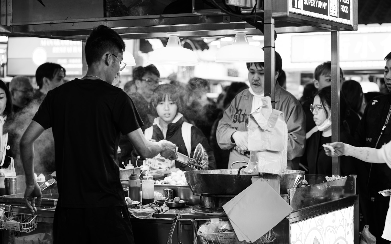 Grupo de pessoas reunidas em torno de uma barraca de comida em feira ao ar livre