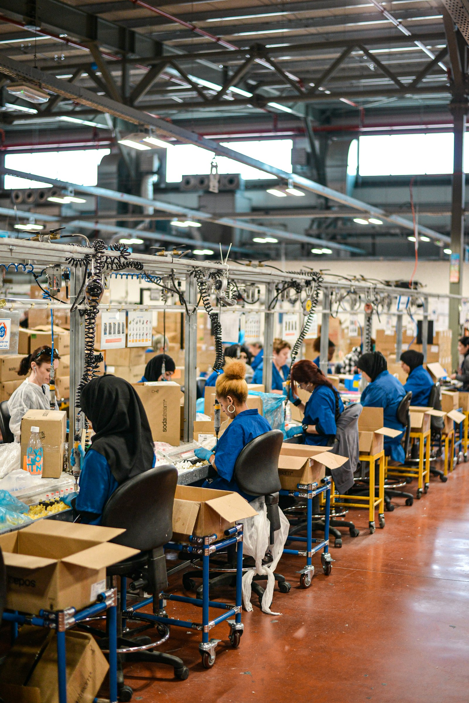Trabalhadores de uniforme azul operando uma linha de montagem em uma fábrica