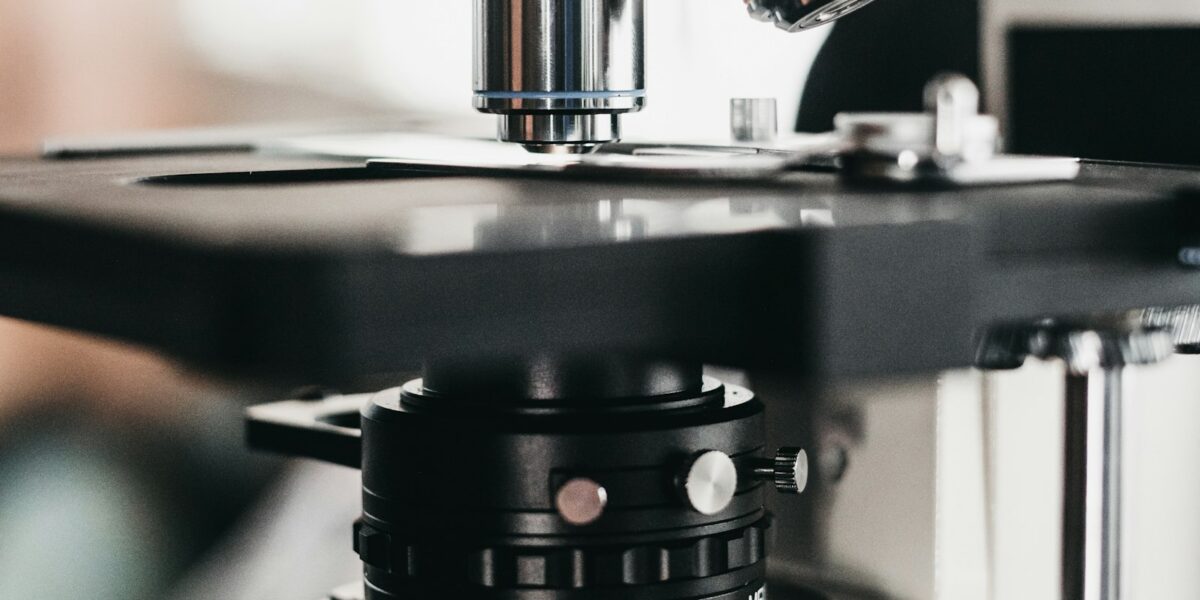 Pesquisador ajusta o foco de um microscópio em bancada de laboratório