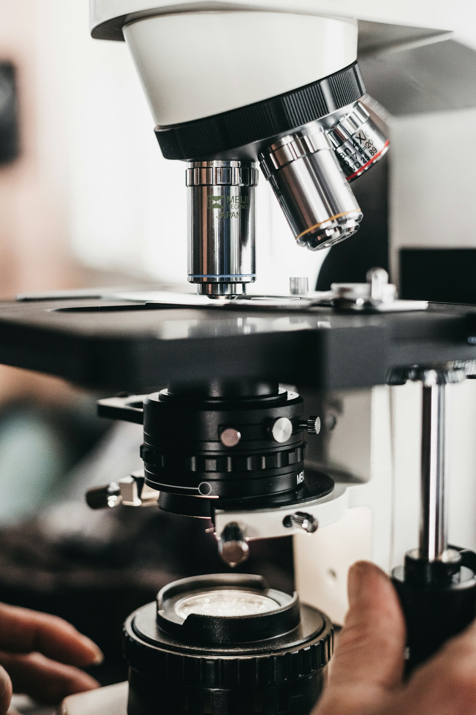 Pesquisador ajusta o foco de um microscópio em bancada de laboratório