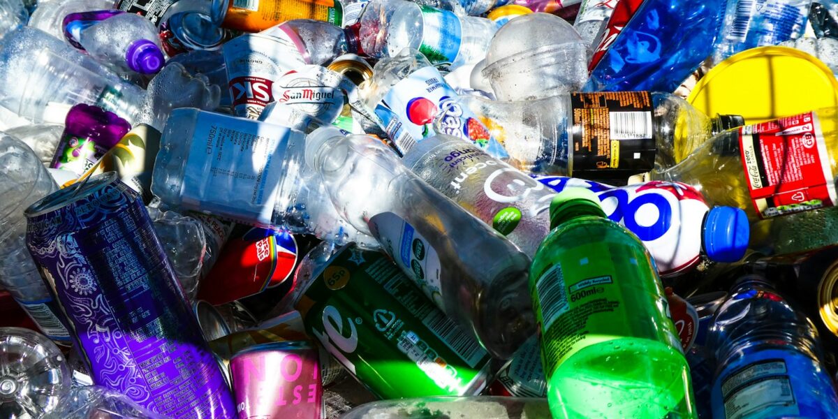 Pilha de garrafas plásticas e latas de alumínio separadas para reciclagem