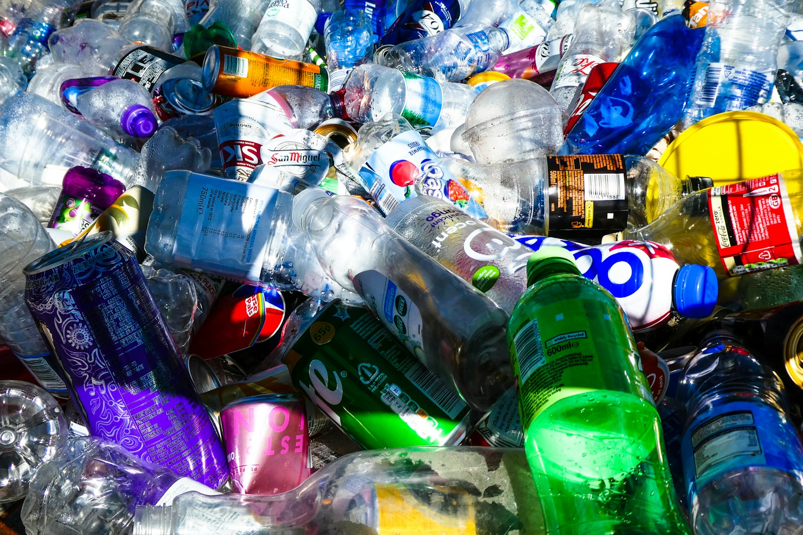 Pilha de garrafas plásticas e latas de alumínio separadas para reciclagem