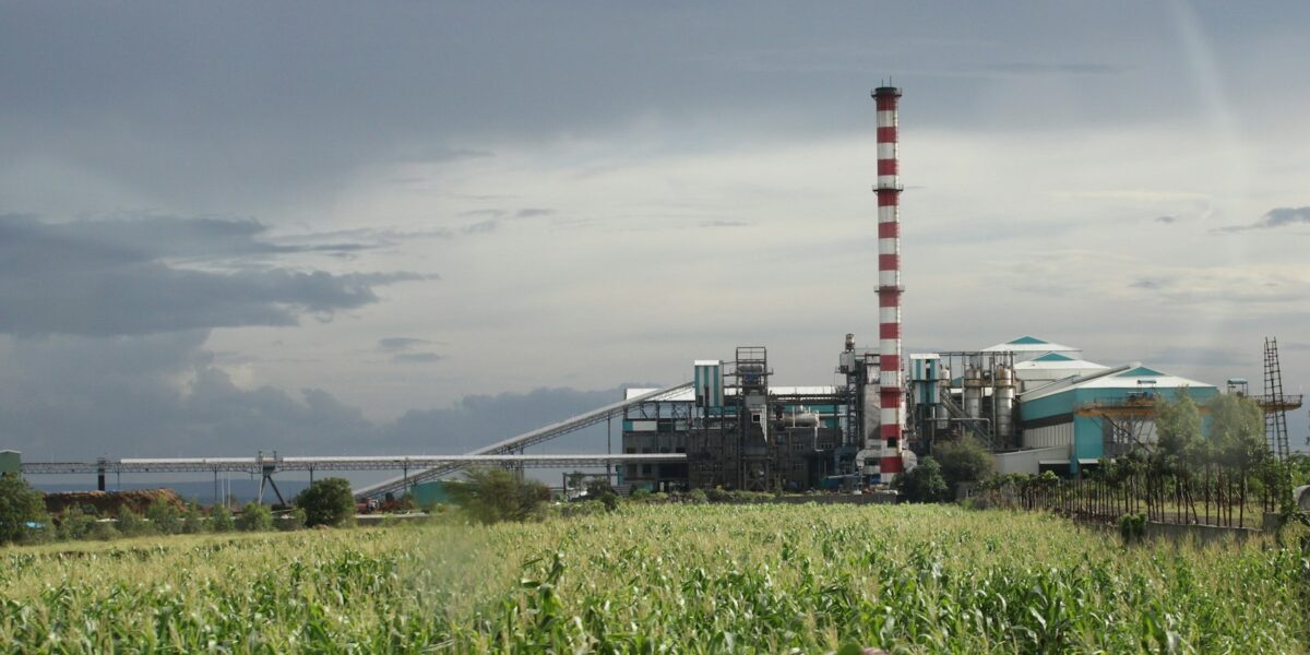 Vista externa de uma planta industrial com tubulações e chaminés