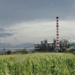 Vista externa de uma planta industrial com tubulações e chaminés
