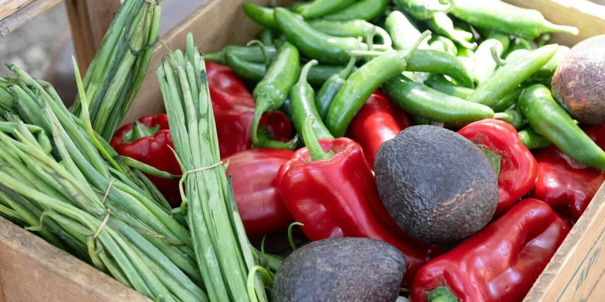 Caixa de madeira cheia de verduras e legumes frescos