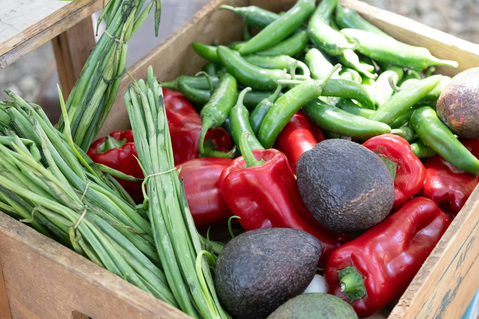 Caixa de madeira cheia de verduras e legumes frescos
