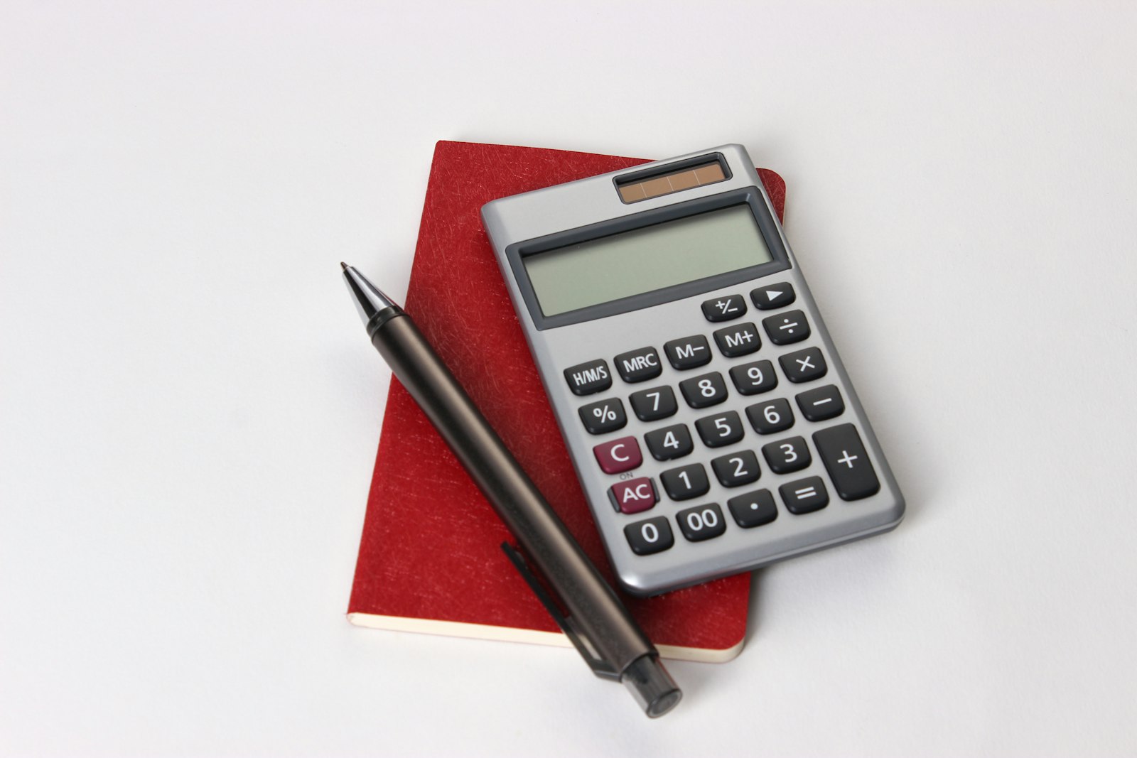 Calculadora preta e prateada ao lado de caneta preta