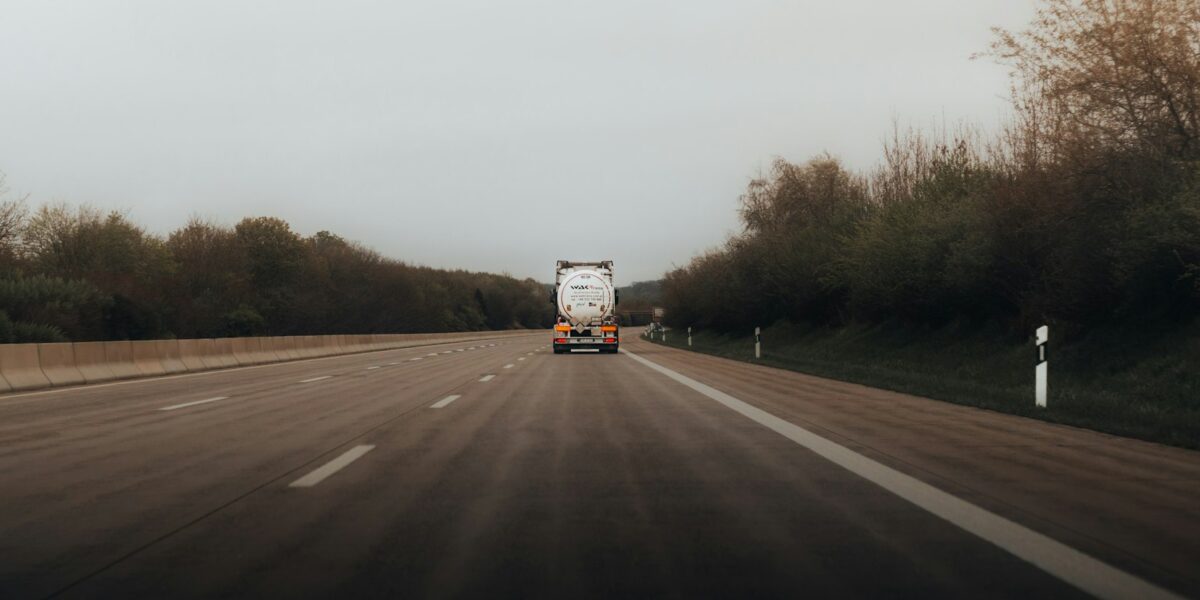 Caminhão de carga trafegando por rodovia ladeada por árvores