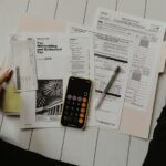 Pessoa segurando papel perto de caneta e calculadora