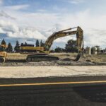 Escavadeira amarela movimentando terra em obra de terraplenagem