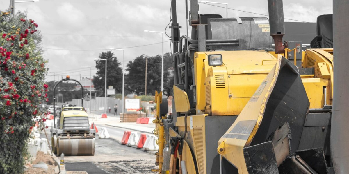 Pavimentadora de asfalto amarela e rolo compressor em obra de rodovia