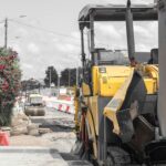 Pavimentadora de asfalto amarela e rolo compressor em obra de rodovia