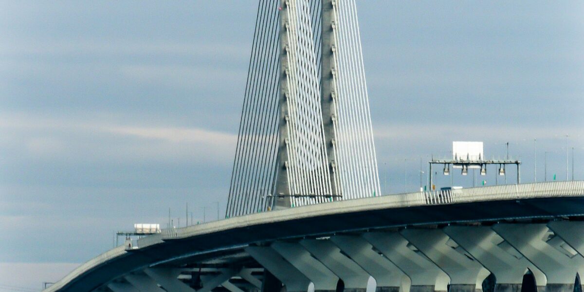 Ponte branca estaiada sobre um rio em dia claro