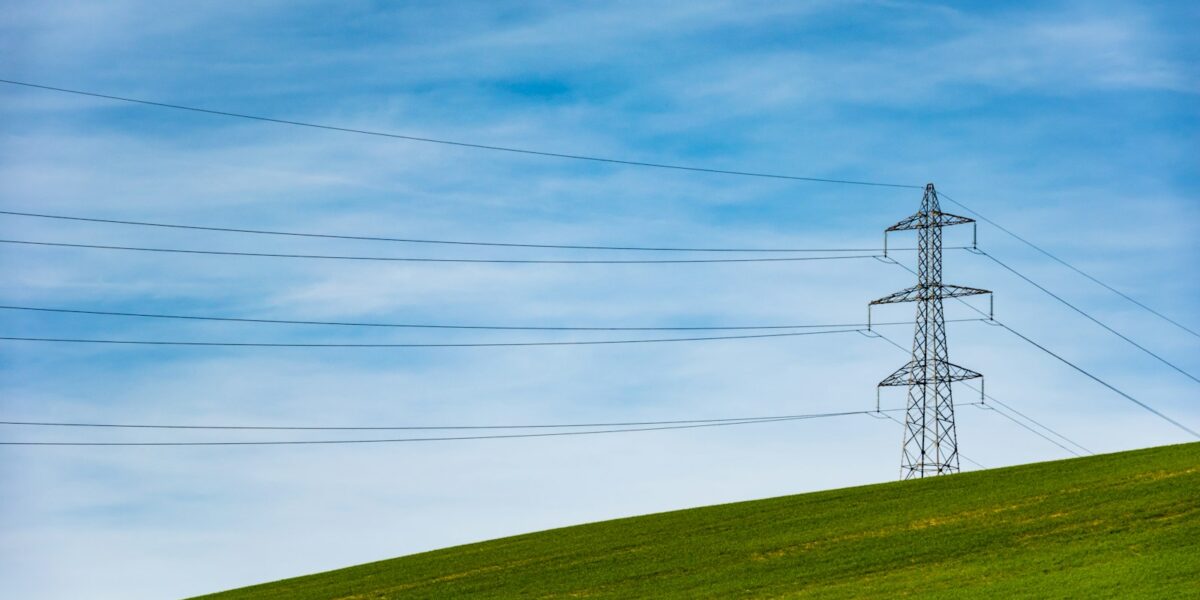 Torre de transmissão de energia elétrica em meio a um campo de grama