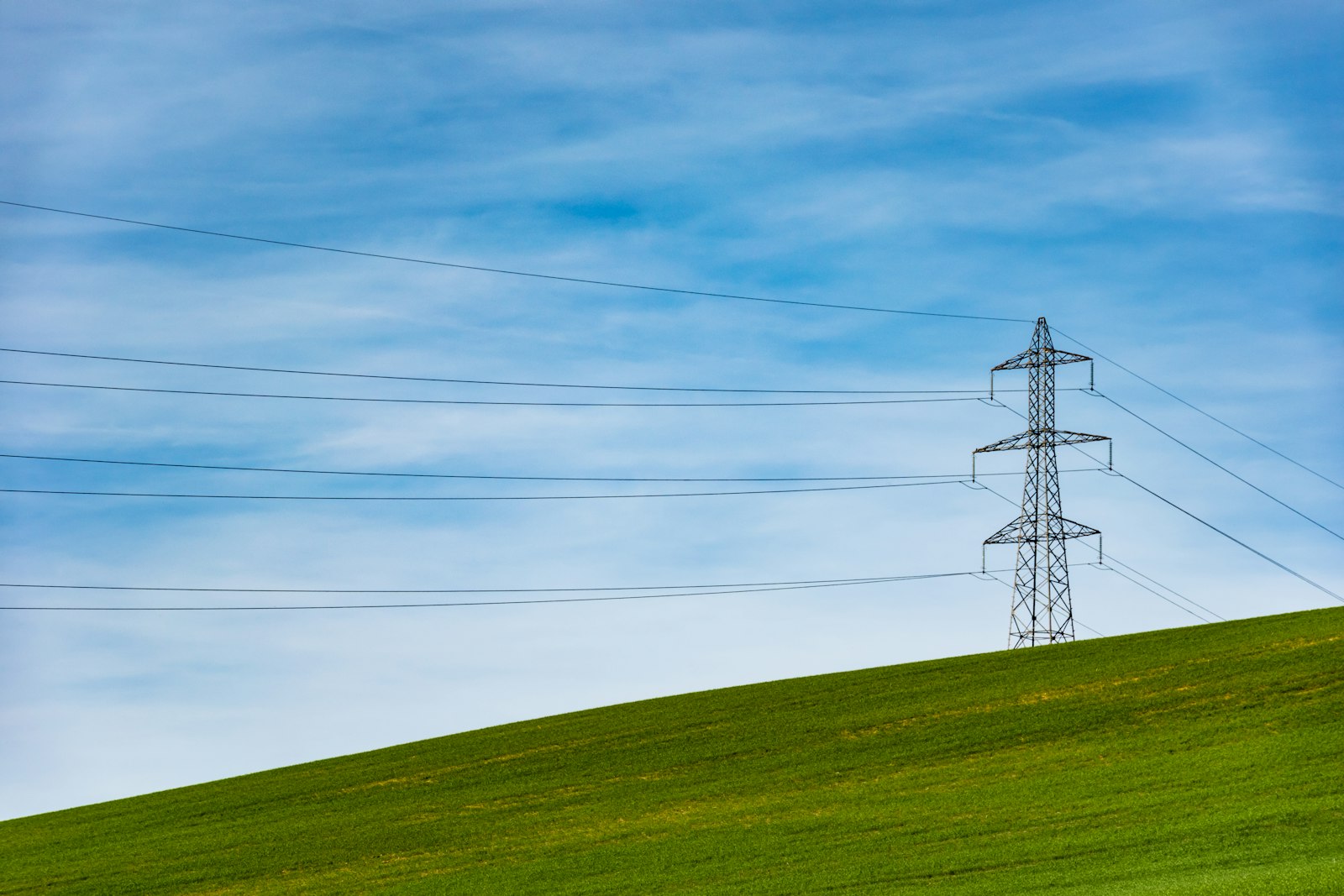 Torre de transmissão de energia elétrica em meio a um campo de grama