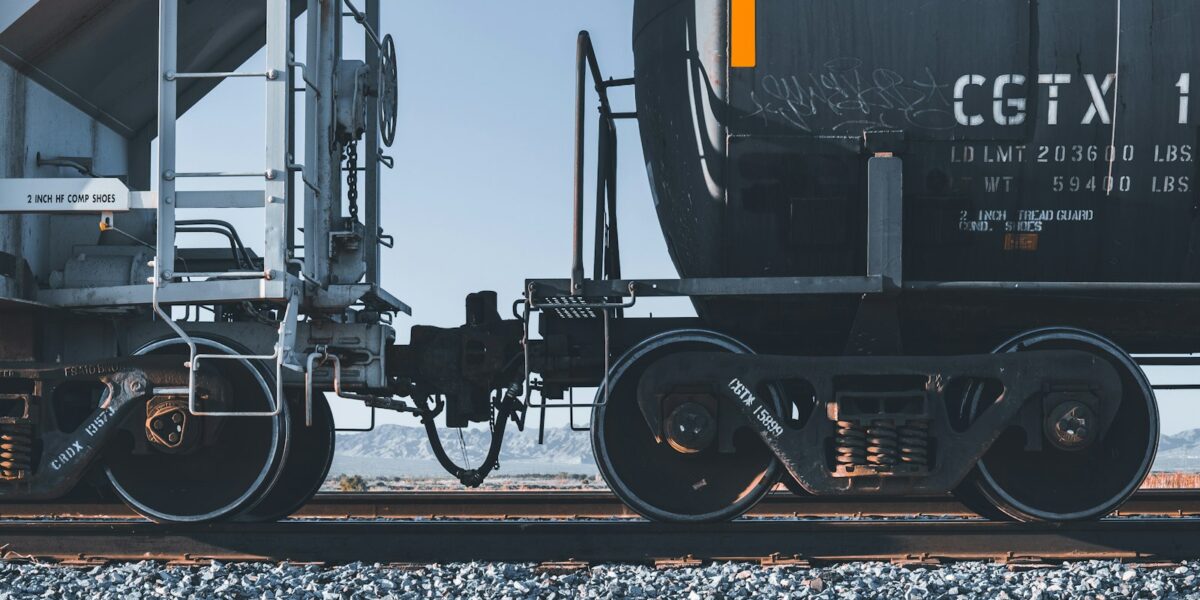 Locomotiva preta e amarela puxando composição de carga sobre trilhos