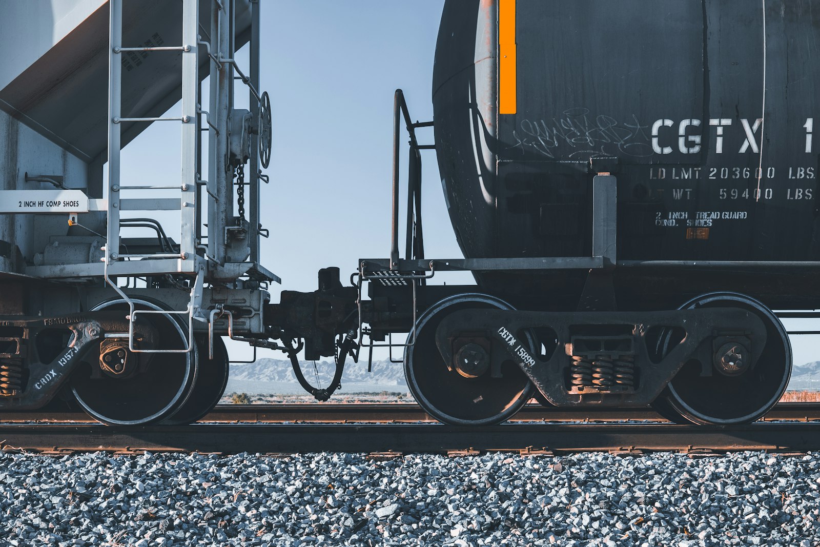 Locomotiva preta e amarela puxando composição de carga sobre trilhos