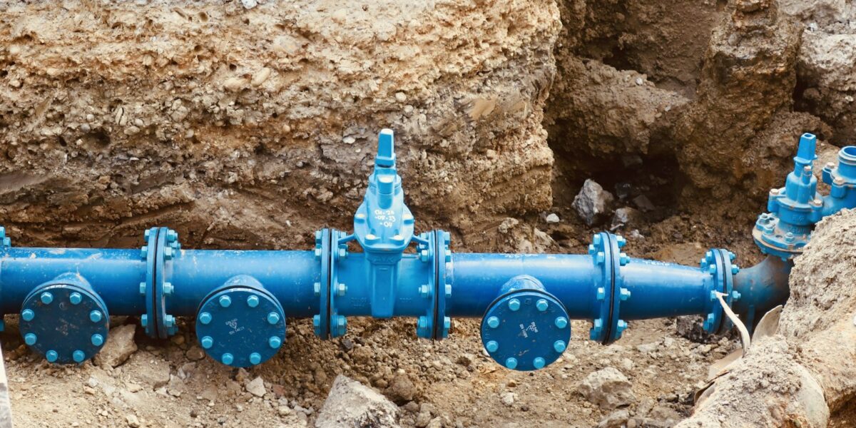 Cano azul de rede de saneamento sobre monte de terra em obra