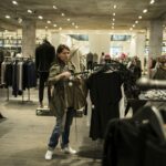 Mulher segura peças de roupa dentro de uma loja de vestuário