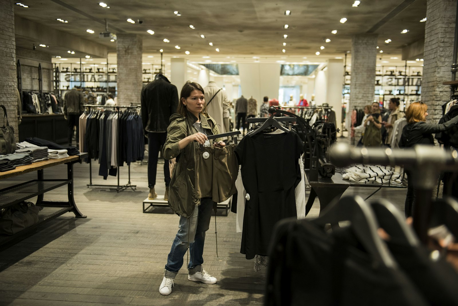 Mulher segura peças de roupa dentro de uma loja de vestuário
