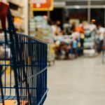 Carrinho de compras azul em corredor de supermercado, imagem ilustrativa