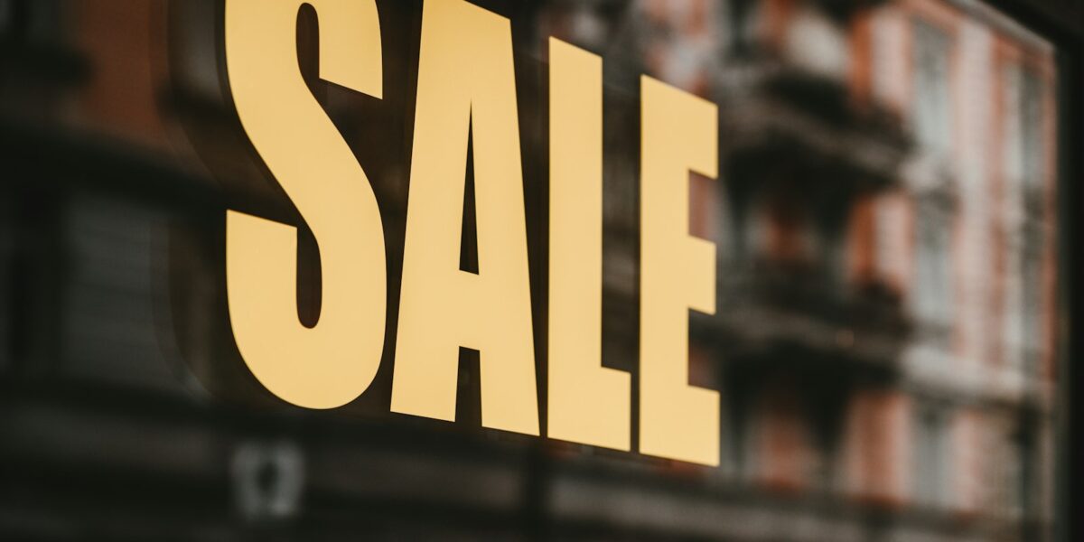 Texto de promoção em letras amarelas impresso no vidro de uma vitrine