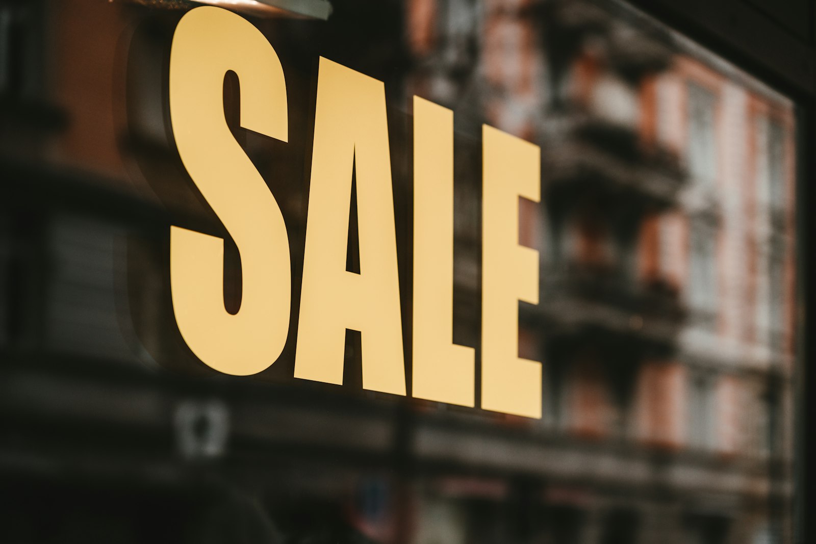 Texto de promoção em letras amarelas impresso no vidro de uma vitrine